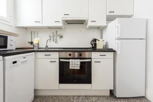 una cocina blanca con armarios y electrodomésticos blancos en Apartamentos Alcalá en Madrid