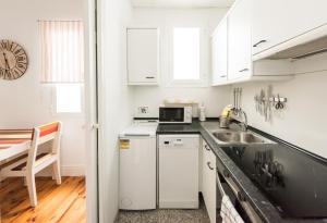 cocina blanca con fregadero y microondas en Apartamentos Alcalá en Madrid
