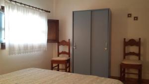 a bedroom with a closet and a door and two chairs at Casa Basciu in Maladroscia