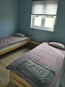 2 łóżka w małym pokoju z oknem w obiekcie Pokoje Gościnne Karkonosze w mieście Wojcieszyce