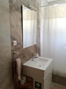 a bathroom with a white sink and a mirror at Casa Pompona 3 in Rogil