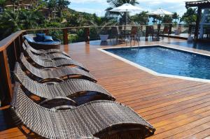 a row of wicker chairs next to a swimming pool at Coronado Inn Hotel in Búzios