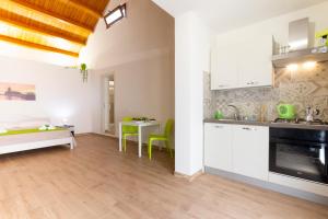 a kitchen with white cabinets and a table with green chairs at Brezza di Stagnone in Birgi Vecchi