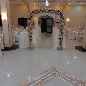 a banquet hall with white tables and a floral arch at Numidien Hotel in Alger