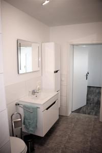 a white bathroom with a sink and a mirror at Pension Bernburg A² in Bernburg +9 photos