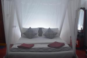 uma cama num quarto branco com almofadas em Samiru Guest Inn Ella em Ella