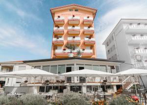 un hôtel avec des tables et des parasols devant lui dans l'établissement Hotel Loreley, à Lido di Jesolo