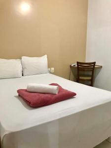 Una cama blanca con una toalla roja. en Acapu Hotel en Rio Verde