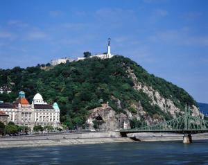 a bridge over the water next to a hill with a castle at Corvinus Apartman in Budapest