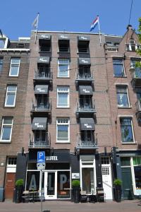 ein großes Backsteingebäude mit Balkonen auf einer Straße in der Unterkunft Alp Hotel in Amsterdam