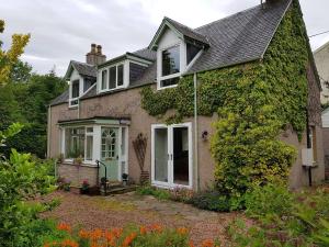 a house with ivy on the side of it at Smithy Cottage in Kirkmichael