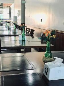 une rangée de tables avec des fleurs dans des vases verts en verre dans l'établissement Acapu Hotel, à Rio Verde