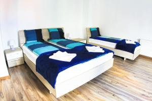 two beds in a room with wooden floors at CENTRAL APARTMAN in Gheorgheni