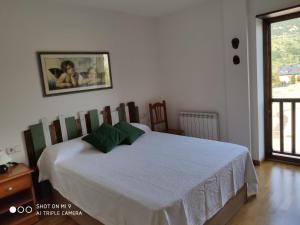 a bedroom with a white bed with green pillows at Apartamento Erta in Pla de l'Ermita