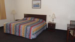 una habitación de hotel con una cama con una manta colorida en Deluxe Inn Palacios, en Palacios
