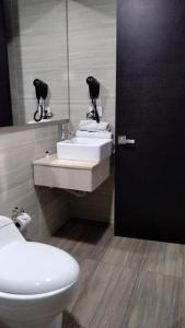 a bathroom with two sinks and a toilet and a mirror at Hotel WLH Bogota - White Lighthouse in Bogotá