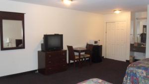 a hotel room with a television and a table with a bed at Deluxe Inn Palacios in Palacios