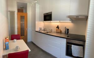 a kitchen with white cabinets and a table with red chairs at Karl&Deby Lugano stazione/centro in Lugano