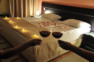due persone che tengono bicchieri di vino davanti a un letto di Hotel Beograd - Yu a Sarajevo