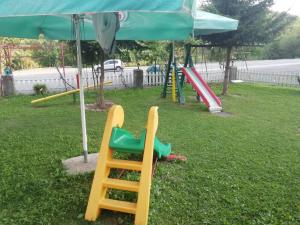 a playground with a slide and an umbrella at Rural haushold Konak Vukovica kolibe in Mojkovac