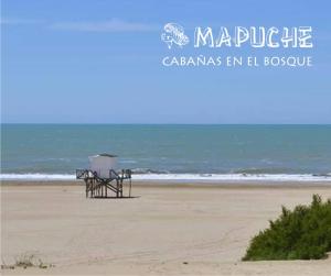 una playa con un banco en la arena y el océano en Cabañas Mapuche en Mar de las Pampas