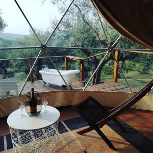 una bañera y una mesa con una botella de vino y una silla en Cerchio Del Desiderio Glamping Retreat, en Pescara