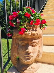 Una estatua de una cabeza con flores. en Mastrissa Country House, en Taormina