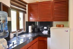 a kitchen with wooden cabinets and a sink and a refrigerator at Playa Palms Beach Hotel in Playa del Carmen