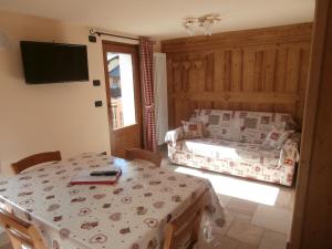 a room with a table and a bed and a television at Petites Fleurs Cogne in Cogne