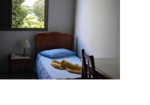 a bedroom with a bed with a blue pillow and a chair at Hotel Sorrento in Belo Horizonte