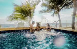 three people sitting in the water in a swimming pool at Hotel Rilux Tolu in Tolú
