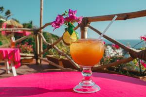 um copo de sumo de laranja numa mesa rosa com uma flor em Hotel Flamingos em Acapulco
