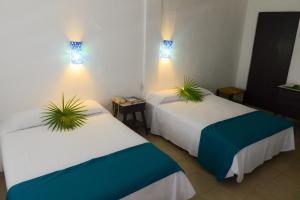 Dos camas en una habitación con dos plantas. en Hotel Flamingos en Acapulco