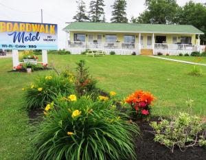 a white house with flowers in the yard at Boardwalk Motel in Cavendish
