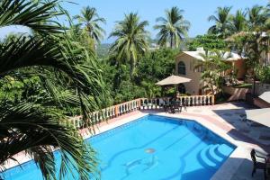a pool in a resort with palm trees at Hotel Barlovento in Puerto Escondido