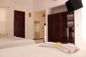 een slaapkamer met 2 bedden met witte lakens en een televisie bij Hotel Barlovento in Puerto Escondido