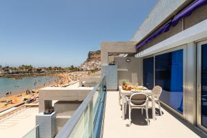 a balcony with a table and chairs and a beach at Amarre Ocean in Puerto de Mogán