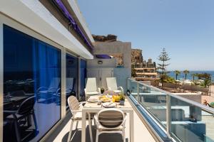 a balcony with a white table and chairs on it at Amarre Ocean in Puerto de Mogán