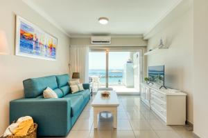 a living room with a blue couch and a view of the ocean at Amarre Ocean in Puerto de Mogán