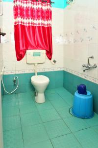 a bathroom with a toilet and a red shower curtain at RK Holiday Home in Ooty