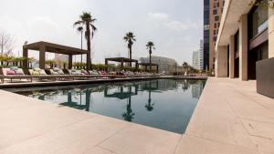 a pool with chairs and palm trees in a building at Miyana Condos by LiveMexicoCity in Mexico City