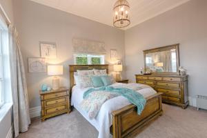 a bedroom with a bed and two dressers and a mirror at Aqua On Reed in Oamaru