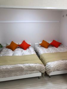 two beds in a room with red and orange pillows at GOLDHOUSE Shinosaka 303 in Osaka