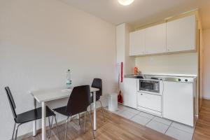 cocina con mesa, sillas y nevera en Anstatthotel Hochdorf - self-check-in, en Hochdorf