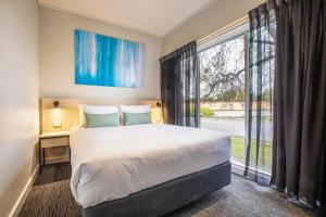 een slaapkamer met een bed en een groot raam bij Nightcap at Excelsior Hotel in Melbourne