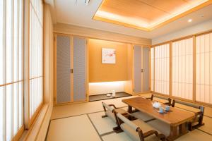 comedor con mesa, sillas y ventanas en Tomonoya Ryokan Geoje, en Geoje