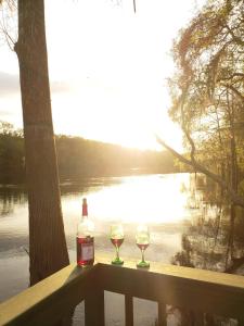 a bottle of wine and two glasses on a bench near a lake at MARGARITAVILLE ON THE SUWANNEE RIVER in Mayo