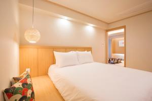 1 dormitorio con cama blanca y lámpara colgante en Tomonoya Ryokan Geoje en Geoje 