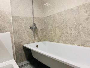 a white bath tub in a bathroom with marble tiles at Horeka Hotel in Ulaanbaatar