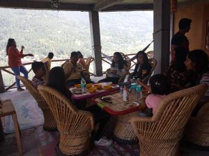 un grupo de personas sentadas alrededor de una mesa en un restaurante en Sunface Homestay, en Manali